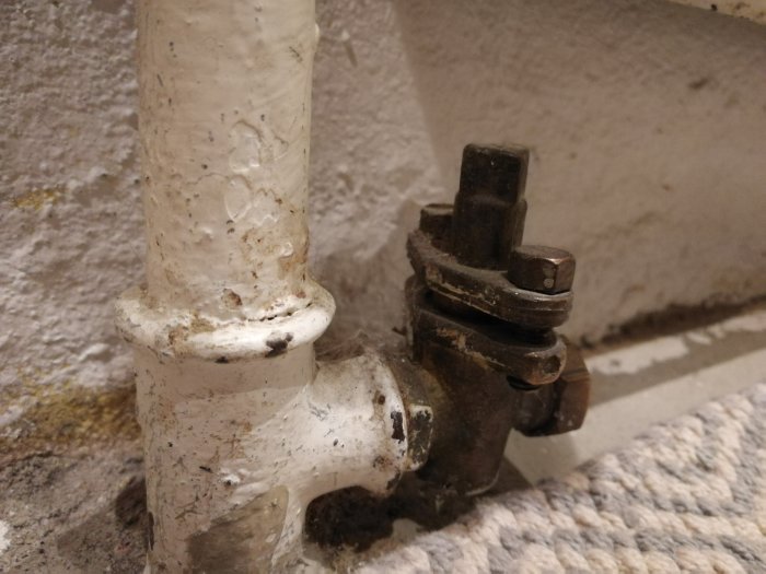 VVS-koppling med plugg på ett vitmålat rör mot en betongvägg, med osäkerhet om dess funktion vid golvflytning.