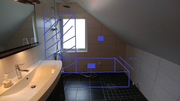 Modernt badrum med snedtak, handfat, blå markerade planer för dusch och badkar samt märkningar för dimensioner.