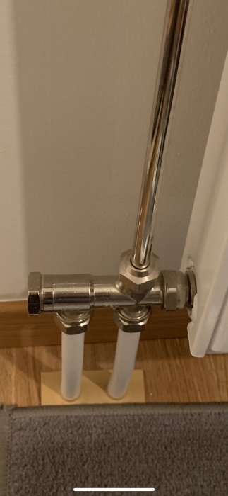 Rördetaljer och kopplingar till ett fungerande radiatorvärmelement i badrum.