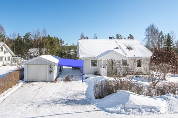 Hus med snötäckt tak och garage, försedd med en digitalt infogad blå carport mellan byggnaderna.