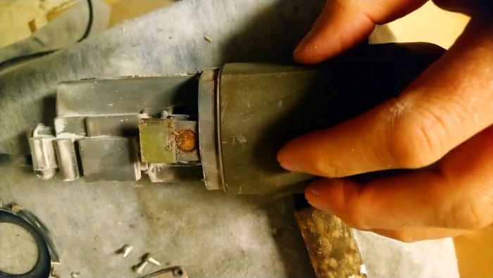 Hand som pekar på en potentiell kolborste inuti motorhuset av en eldriven handverktyg.