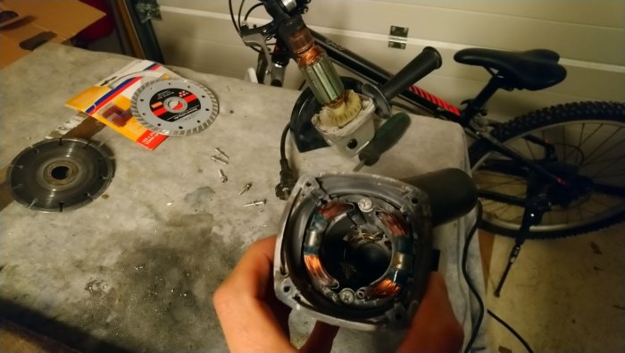 Nermonterad elektrisk verktygsmotor med synliga koppartrådar, i en verkstadsomgivning med cykel och verktyg.