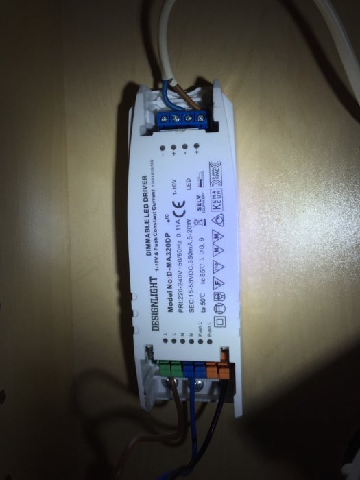 Elektronisk LED-dimmer på vägg med inkopplade kablar och tydliga etiketter.