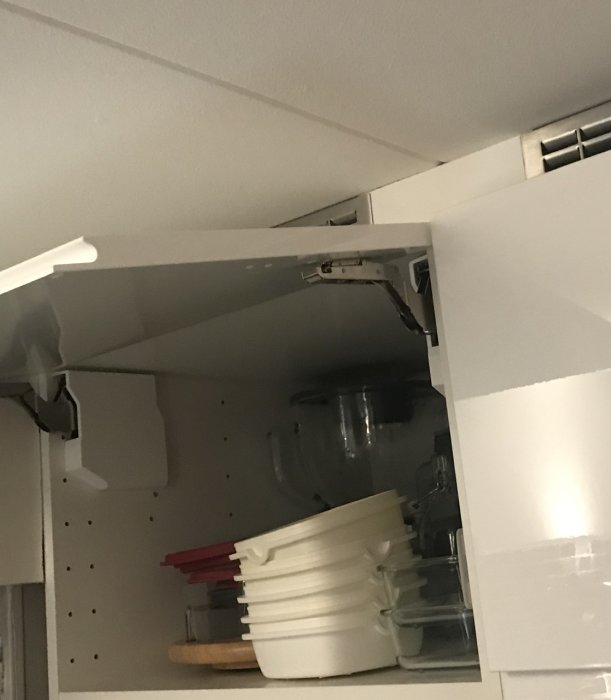 Bild på öppet skåp med Ikeas Utrusta gångjärn synligt på en horisontellt upphängd dörr.