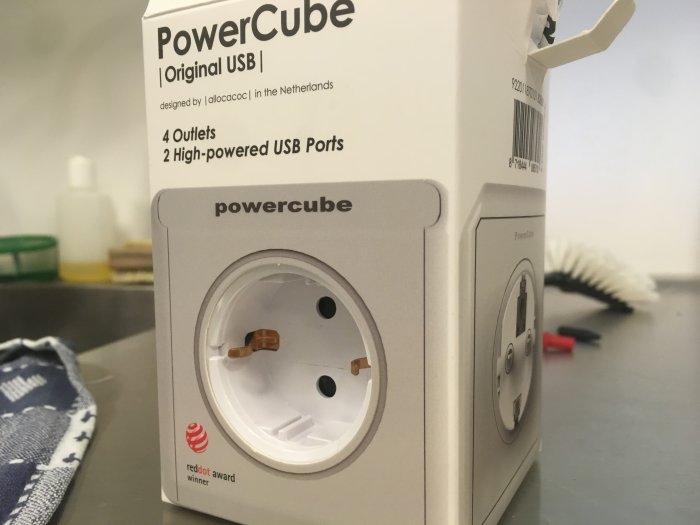 Närbild av en Powercube grenuttag med en eluttag och fyra USB-portar på köksbänk, kopplad till ett uttag.