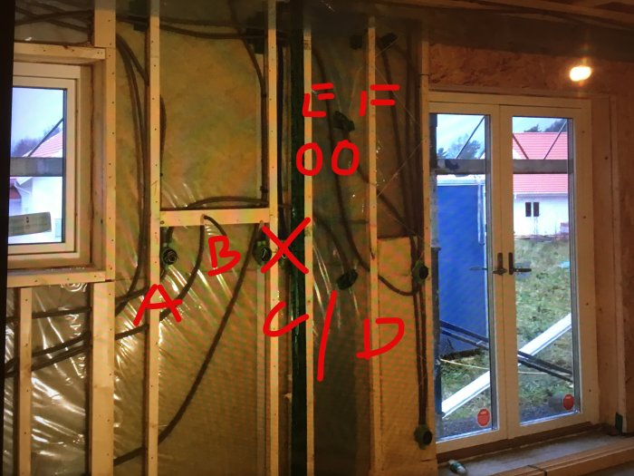 Öppen vägg med isolering och elektriska uttag märkta A till F, i ett nybyggt hus under köksrenovering.