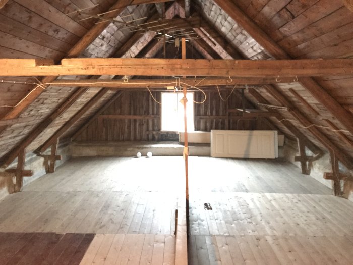 Gammal vind med synliga takstolar, 15 cm tjocka balkar, hanbalkar, utan stödben och två typer av takbeläggning.