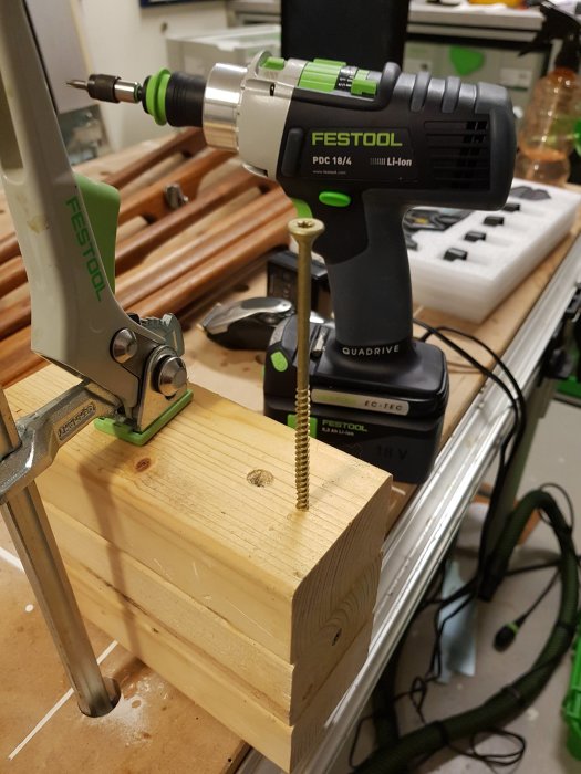 Festool skruvdragare som sätter i en stor skruv i träblock fastsatt med klämma.