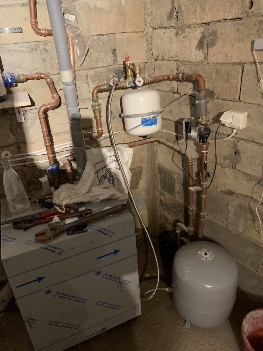 VVS-installation med expansionskärl, ledningar och ventiler i ett källarutrymme.