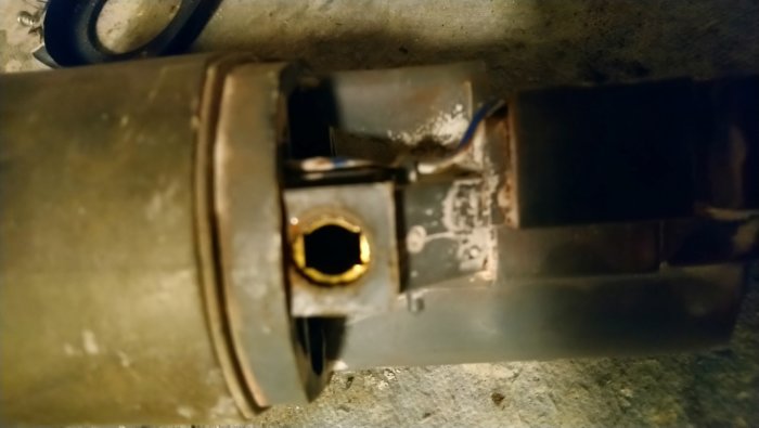 Bild av ett hål där ett kol har tagits bort från en elektrisk motor, med synliga rester och möjlig isolering.