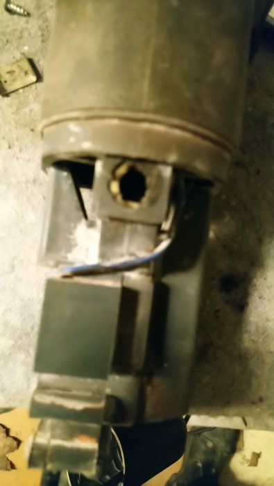 Närbild på en vinkelslip motor med ett kol som sitter fast och synlig smuts eller lack i hålet.