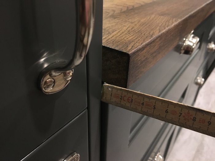 Gap mellan bänkskiva i trä och köksstomme med måttstock som visar bredden.