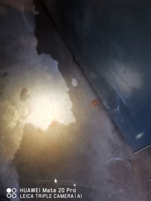 Vattenläckage i garage med fuktfläckar och rost på vägg och golv.