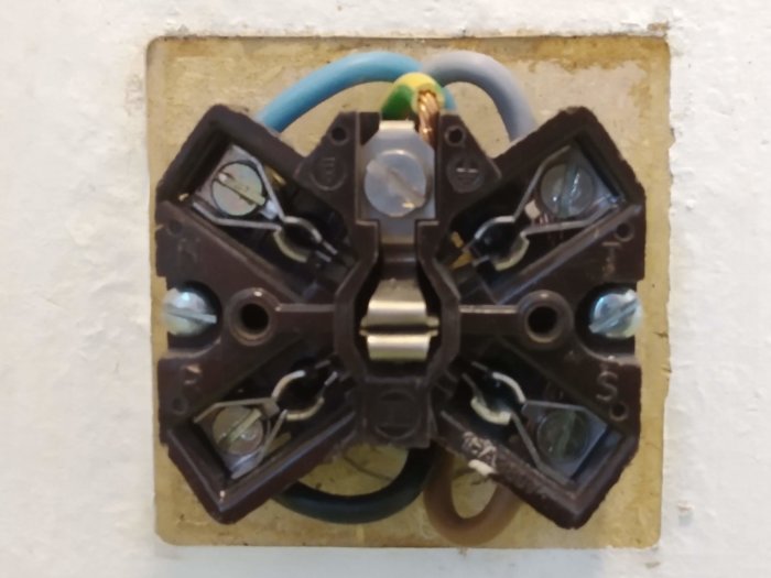 Väggkontakt för spis med framdragna kablar och oanvänd nollplats, sett rakt framifrån.