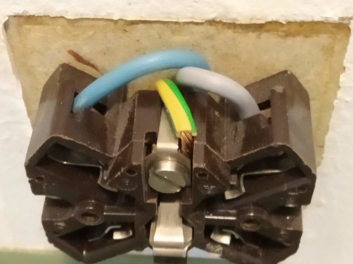 Väggkontakt för spis med blå, gul/grön och grå sladdar synliga samt oanvänd nollplats.