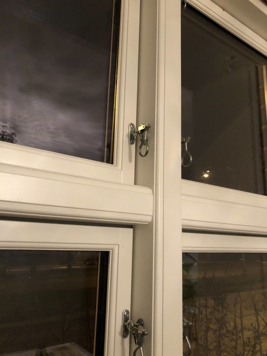 Närbild på en vit fönsterram med en öppen fönsterhasp och oavslutade fönstersmygar.