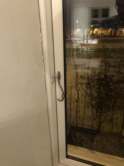 Inomhusvy av ett ofärdigt fönster med synlig fönstersmyg och handtag, reflektion av fotograf syns.