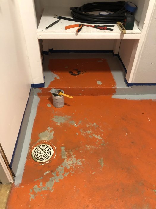 Nymålat orange betonggolv i pannrum med färgburk och verktyg.