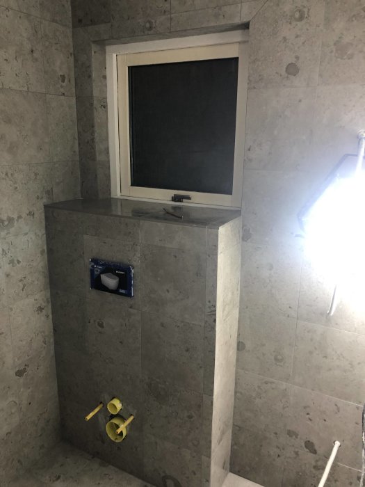 Badrum under renovering med gråa Brickmate Norrvange J33 plattor och väggmonteringsarbete.