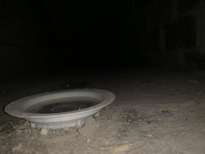 Nedsläckt bild av en golvbrunn på en rå betongyta, möjliga förberedelser för gjutning.