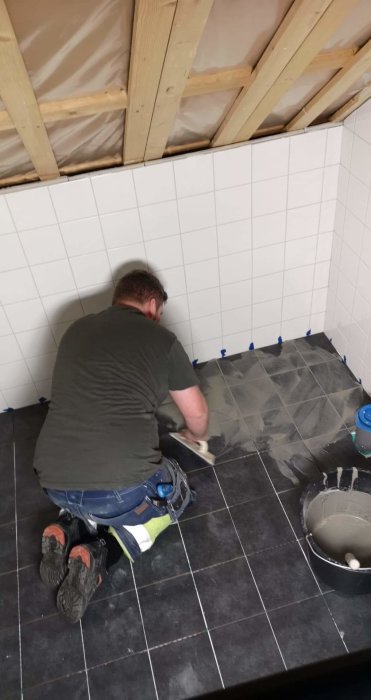 Person fogar kakel i ett halvfärdigt badrum.