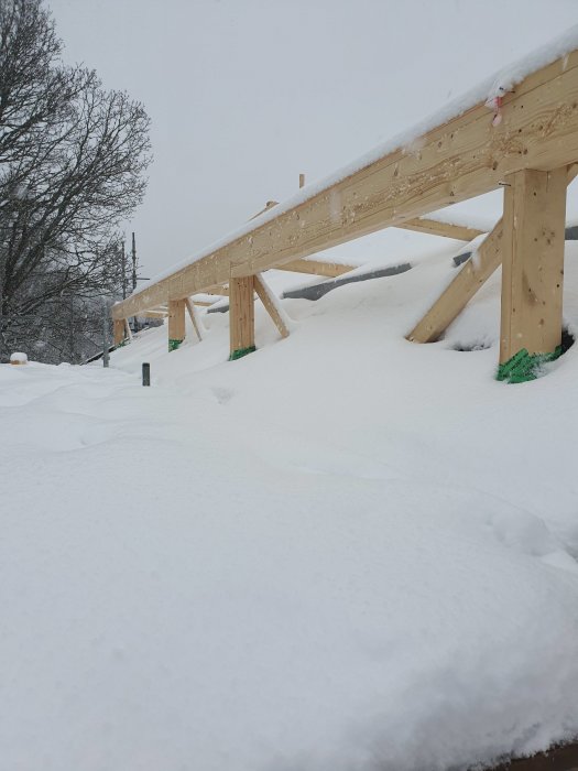 Byggställning i trä täckt med snö i väntan på montering av limträbalk.