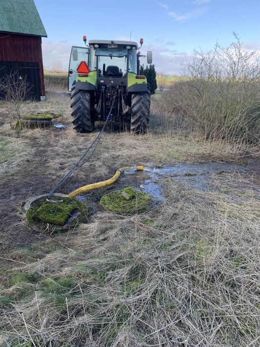 En traktor pumpar vatten från en mossig och övertäckt brunn på en övergiven gårdstomt.