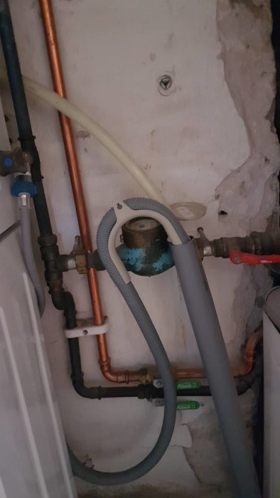 Rörinstallation med vattenmätare, kopparledningar och slangar utan synlig avstängningsventil i källare.