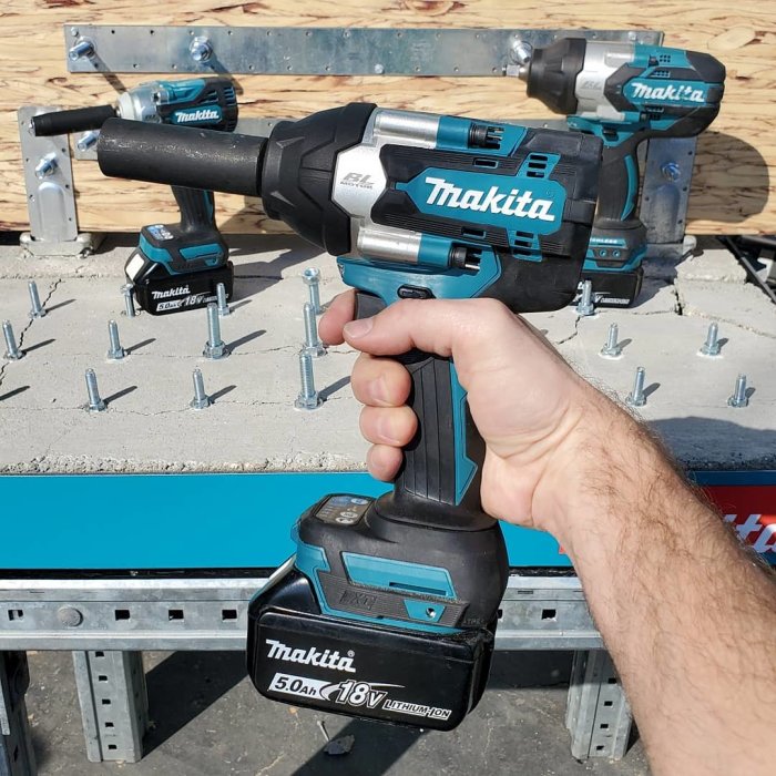 Hand håller en Makita borstlös muttermaskin med 18V-batteri framför andra Makita verktyg.