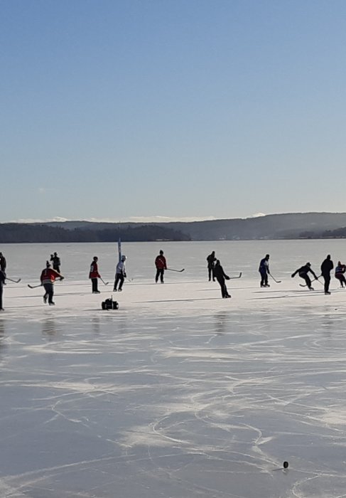 Personer spelar hockey på en isbelagd sjö under lunchpausen.