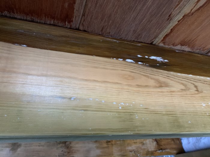 Ofärdigt trätrappsteg med fläckar av spackel eller målarfärg längs kanten och på ytan.