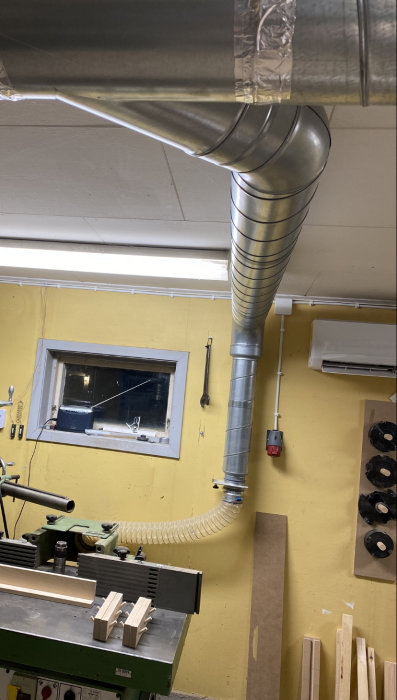 Installation av ventilationssystem med spiro-rör och flexslang ovanför verktygsmaskin i verkstad.