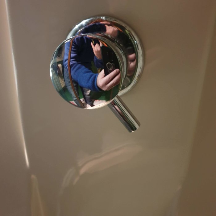 Nyinstallerad dörrhandtagsspegel med reflektion av en person som fotograferar.