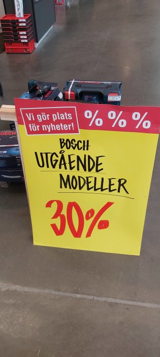 Reaskylt med text "BOSCH UTGÅENDE MODELLER 30%" i en butik, verktyg visas i förgrunden.