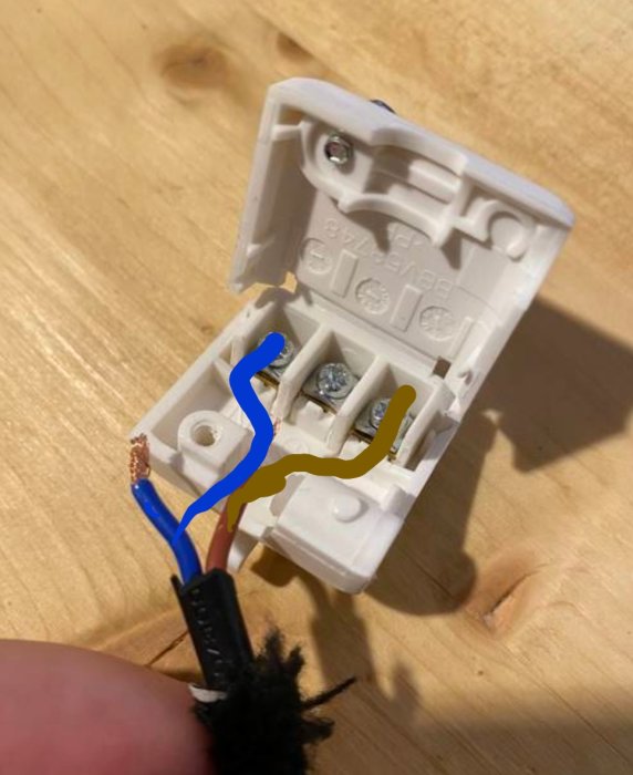 Öppen elektrisk kopplingsdosa med en skruv i mitten och två yttre, kablar ej korrekt anslutna.