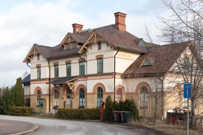 Gammal nationalromantisk järnvägsstation med dekorativ tegelfasad och snickarglädje.