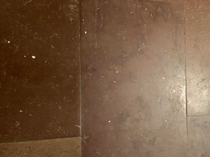 Kalkstensgolv med vita fläckar och tecken på slitage.