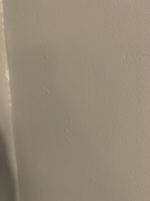 Vägg med små blåsor i färgen liknande månens yta, misstanke om målad tapet under.