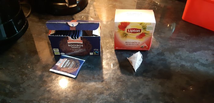 Två olika typer av teförpackningar på en bänkskiva, en i papper och en i plast.