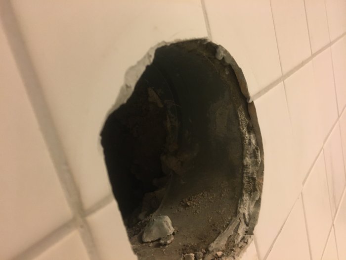 Otydligt silikontätat hål i kakelvägg där en väntad våtspärr syns ej.