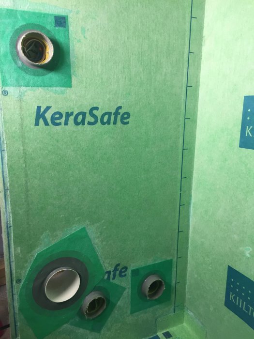 Tätskikt med installerade manschetter runt ventilations- och eluttagsrör på en vägg under renovering.