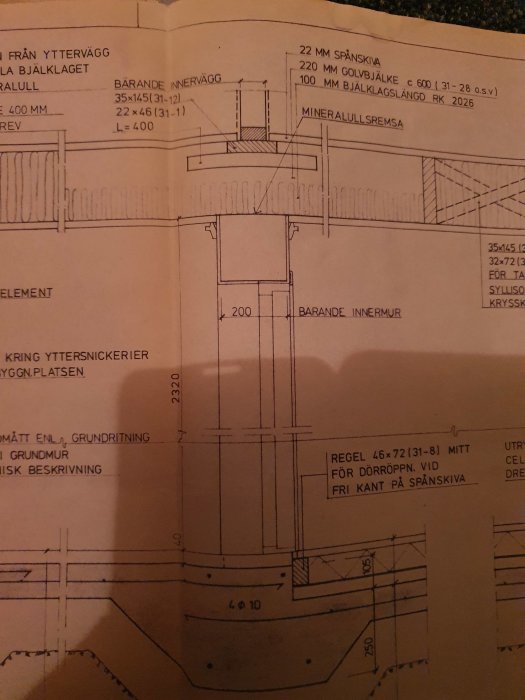 Teknisk ritning av en huskonstruktion som visar en bärande innervägg och detaljerade mått för takstolar och bjälklag.