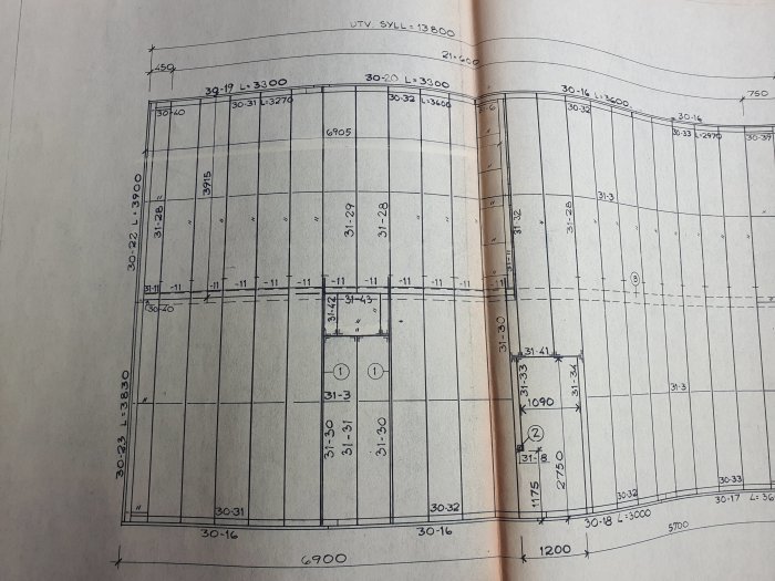 Öppnad sida av arkitektonisk ritning med måttangivelser och layout för en byggnadsplan.