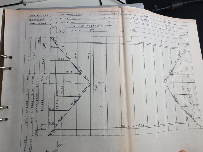 Ritningsdiagram för byggprojekt med mått och detaljer i uppslagen bok.