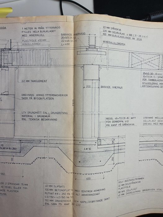 Öppen bok med tekniska ritningar och detaljerade sektioner för byggnadskonstruktion, inklusive mått och materialspecifikationer.