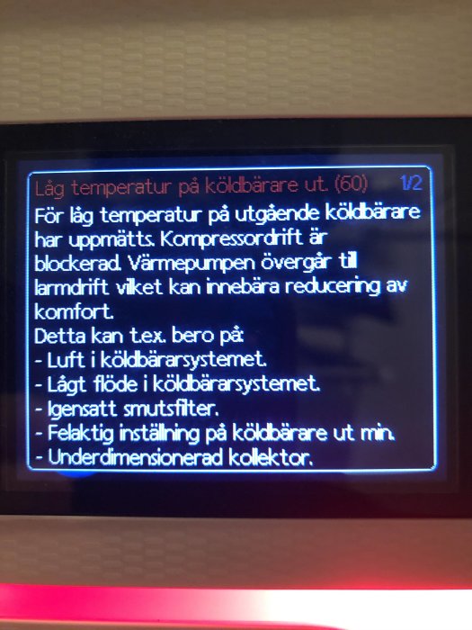 Felmeddelande på värmepumpsdisplay: "Låg temperatur på köldbärare ut" med potentiella orsaker.