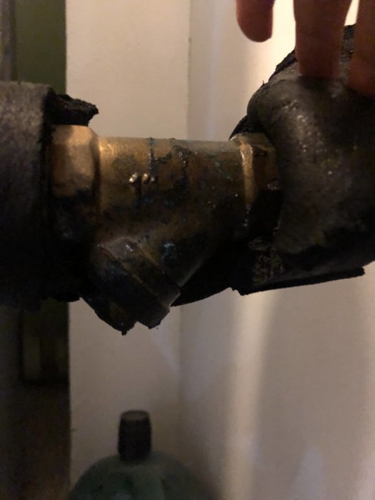Närbild på en hand som rör vid ett rörsystem, troligen en del av en värmepump eller liknande installation.