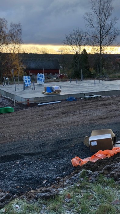 Nygjutna betongplattor för garage och hus i byggprojekt med material och verktyg synliga.