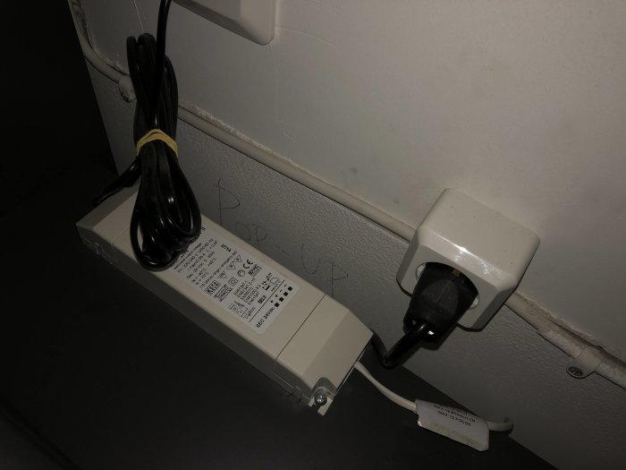 Elkontakt med sladd som är ihopknuten samt en strömbrytare på en vägg.