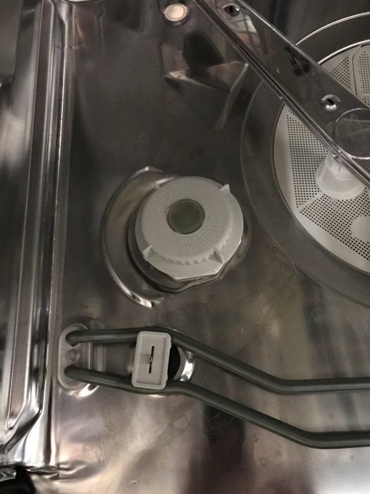 Saltpåfyllningslocket i en diskmaskins botten, nära spolarm och vattenmjukgörarens inställningsknapp.